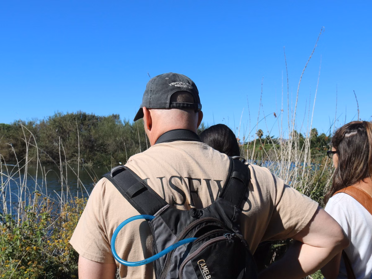 A naturalist leading a small group on a guided walk beside a pond